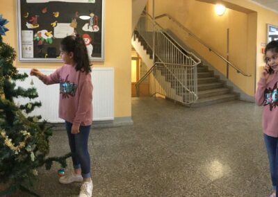Ein bearbeitets Foto mit einem Mädchen in zwei verschiedenen Positionen. Auf der rechten Seite steht sie und telefoniert mit dem Smartphone. Auf der linken Seite steht sie neben einem geschmückten Weihnachtsbaum.