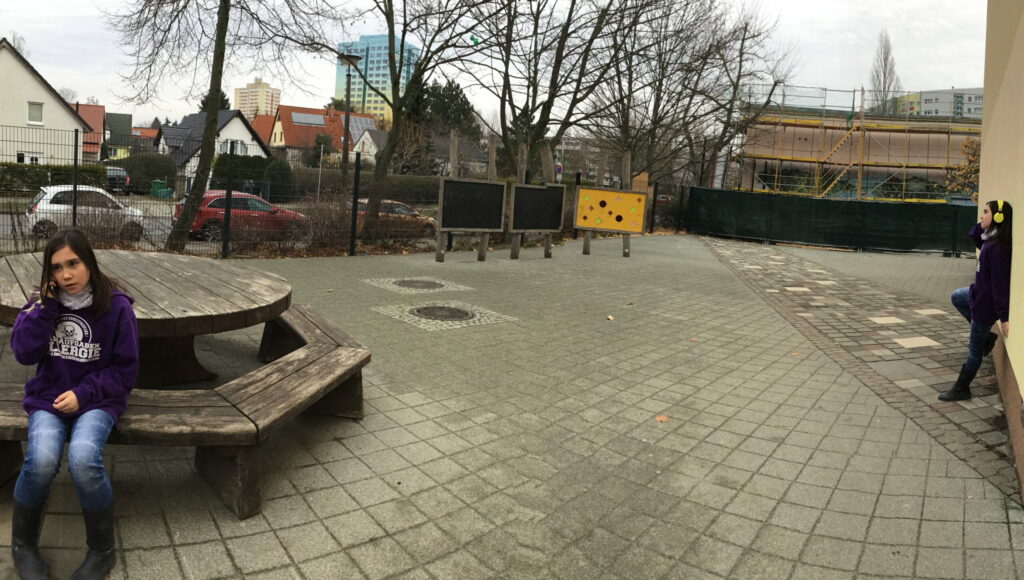 Ein bearbeitets Foto mit einem jungen Mädchen Auf dem Schulhof in zwei verschiedenen Positionen. Auf der rechten Seite lehnt sie sich an eine Wand und hört Musik mit Kopfhörern. Auf der linken Seite sitzt sie auf einer Bank und telefoniert sie mit dem Smartphone