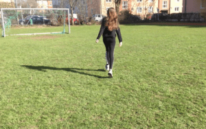 Ein Mädchen steht alleine auf einem Fußballfeld