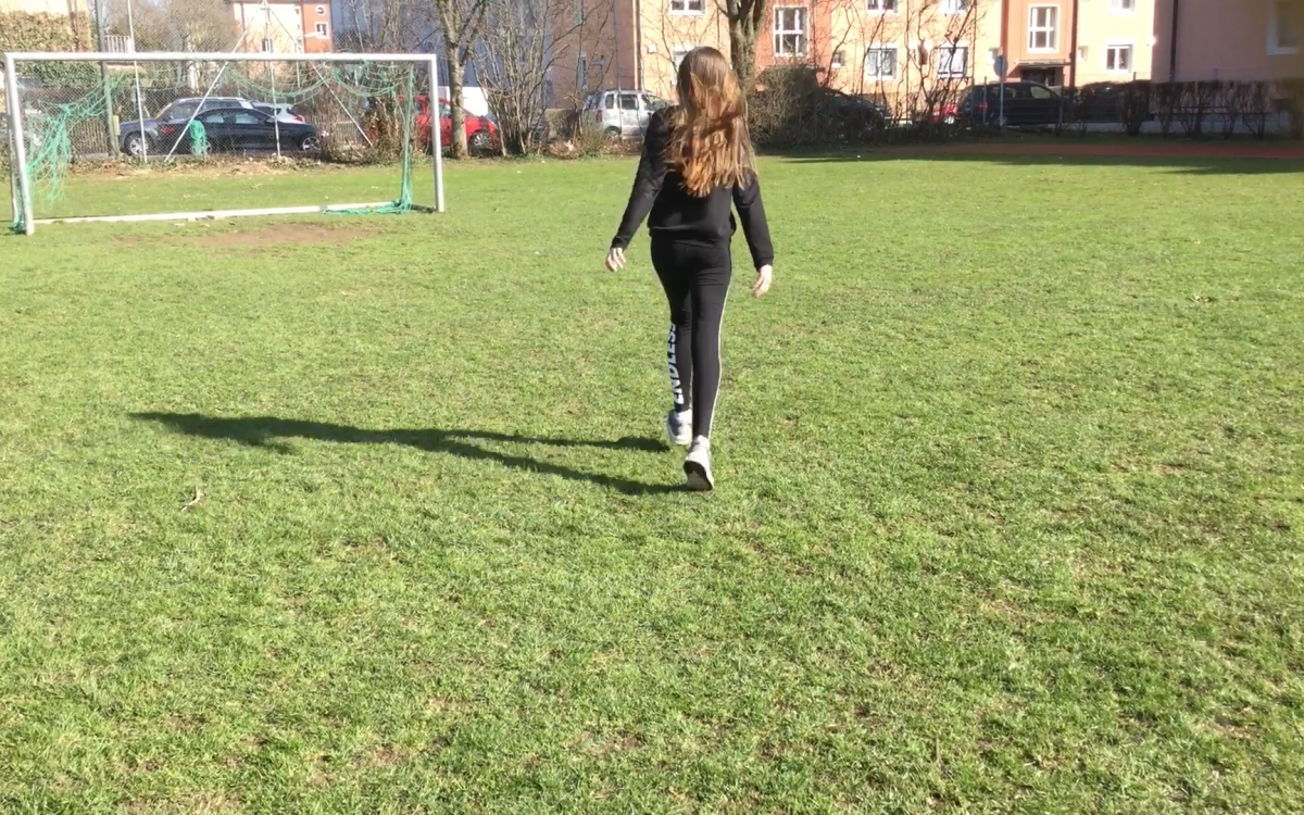 Ein Mädchen steht alleine auf einem Fußballfeld
