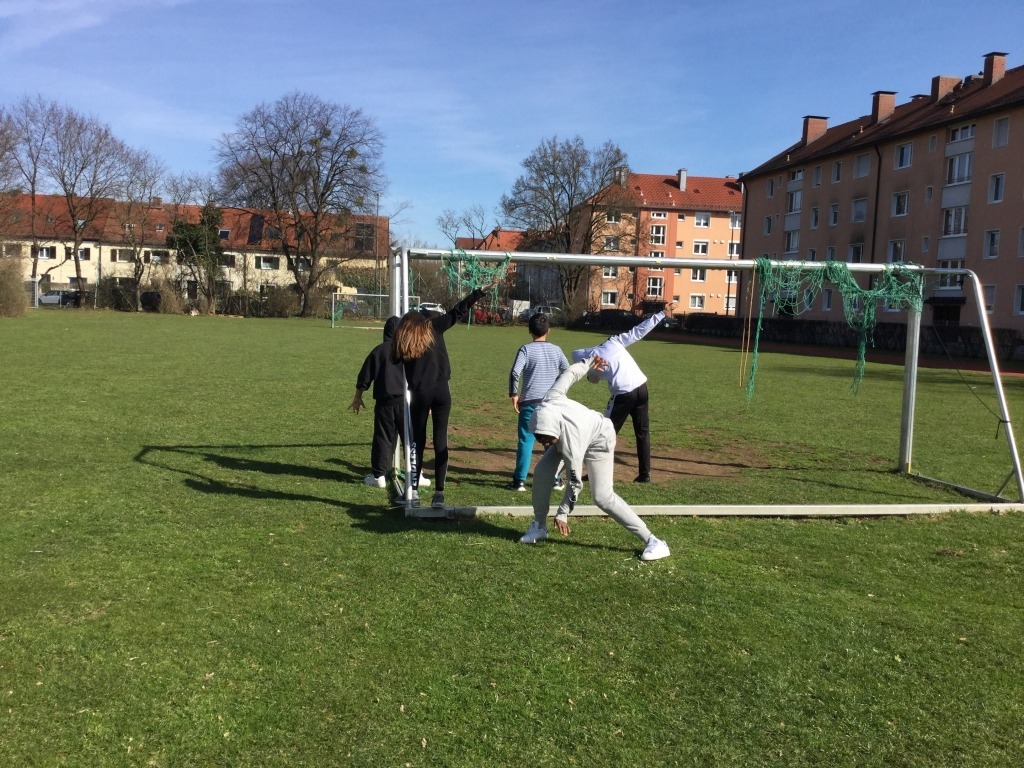 Fünf Kinder stehen auf einem Fußballfeld vor dem Tor.