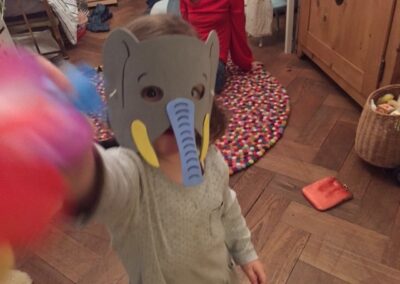 Ein kleines Mädchen mit einer Elefantengesichtsmaske.