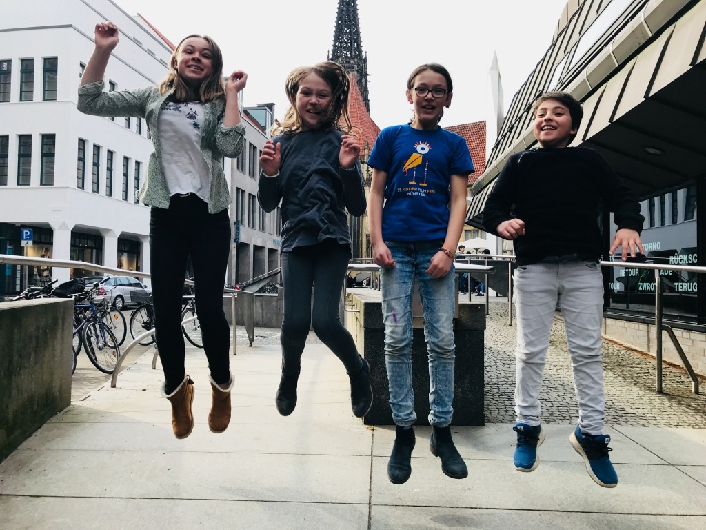 Vier kinder springen in die Luft und sie lachen dabei.