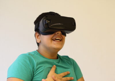 Ein Junge trägt eine Virtual-Reality-Brille und er lacht dabei.
