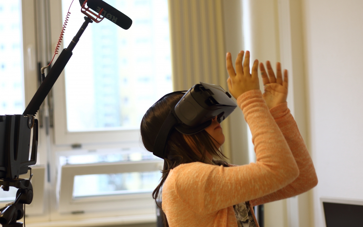 Ein Mädchen trägt eine Virtual-Reality-Brille. Auf der linken Seite des Fotos ist ein Mikrofon zu sehen.