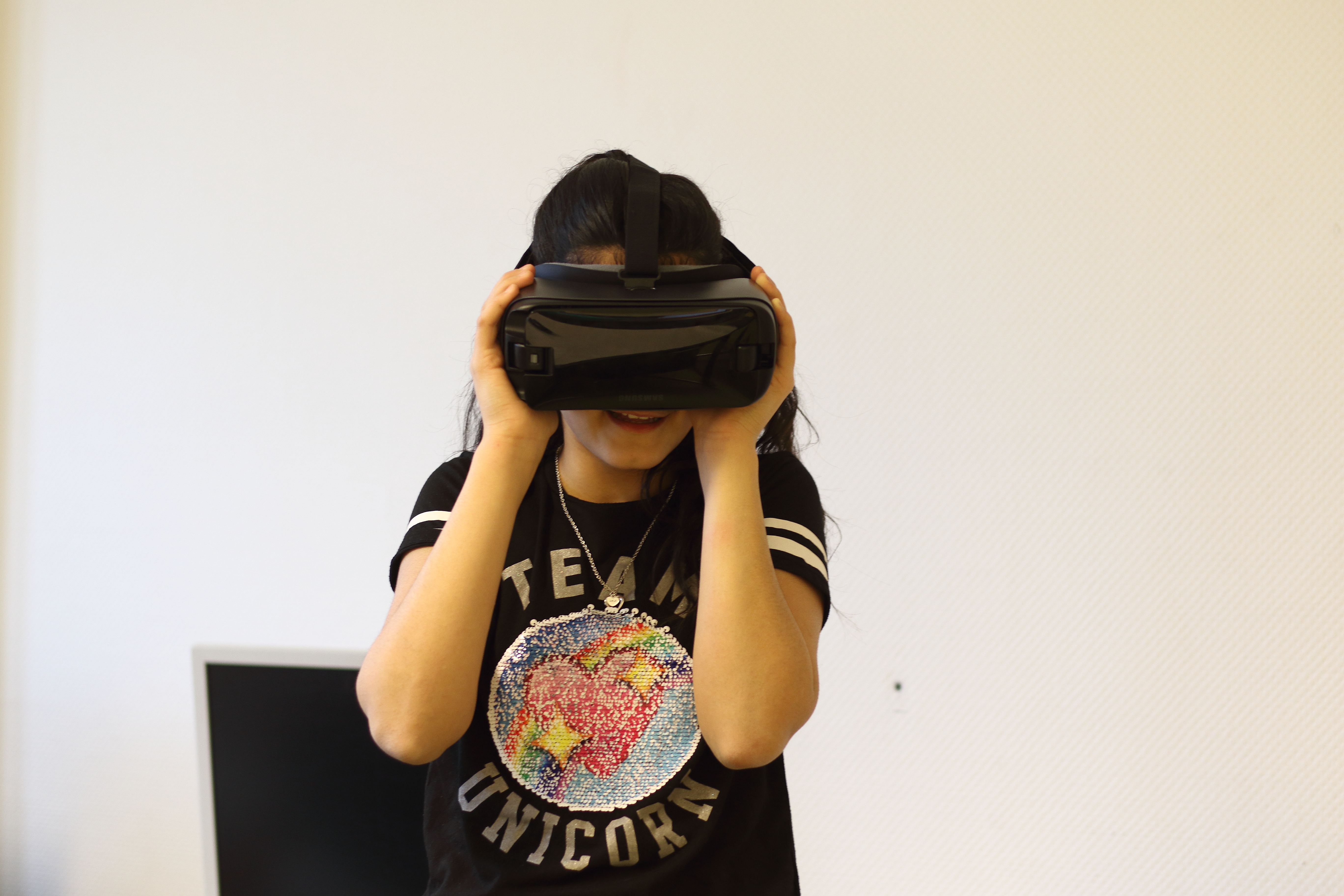 Ein Mädchen trägt eine Virtual-Reality-Brille und sie lacht dabei.