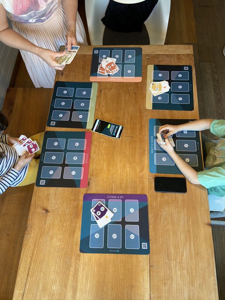 Kinder sitzen am Tisch und spielen ein Kartenspiel.