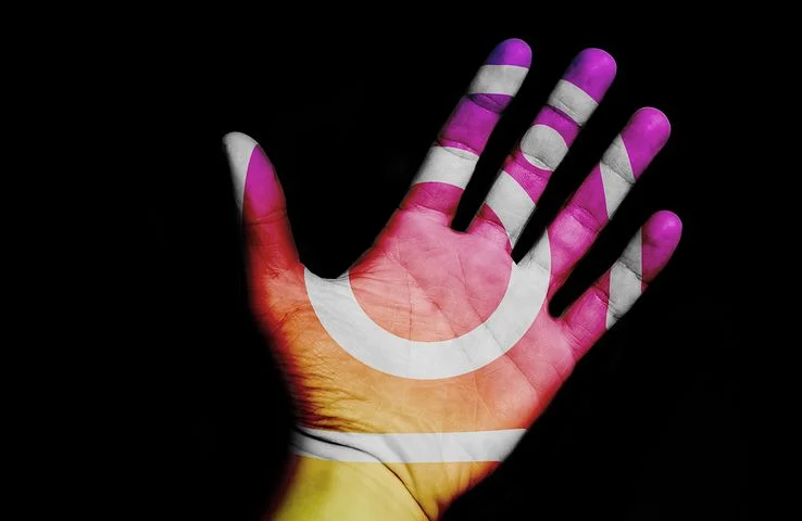 Eine Hand vor einem schwarzen Hintergrund. Aud der Hand erkennt man das Logo von Instagram