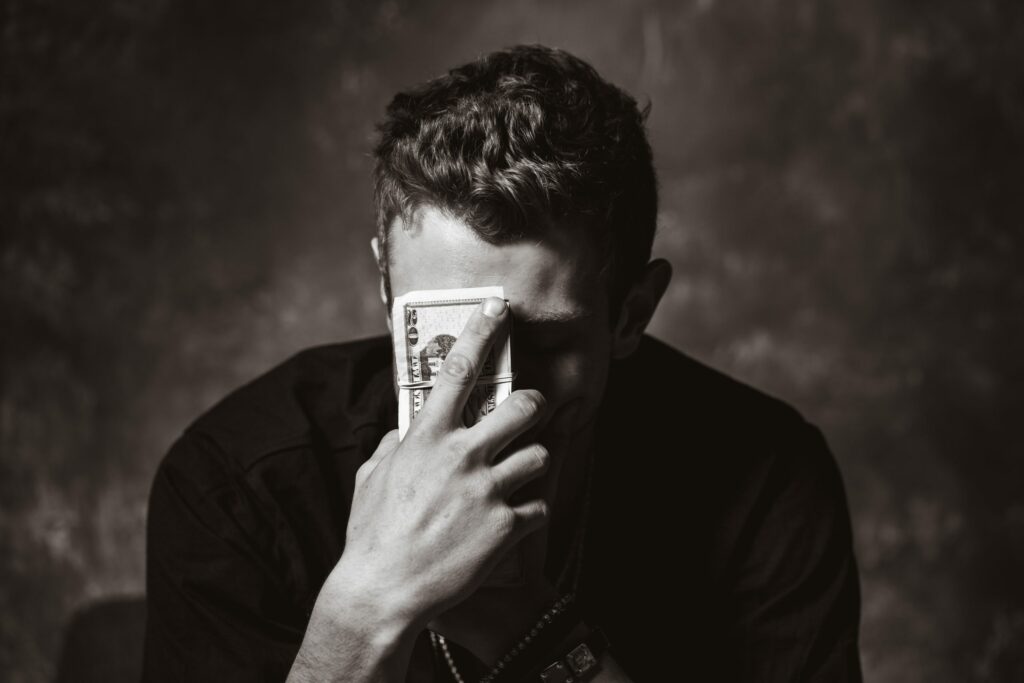 Ein Mann hält Geld mit seiner Hand ins Gesicht.